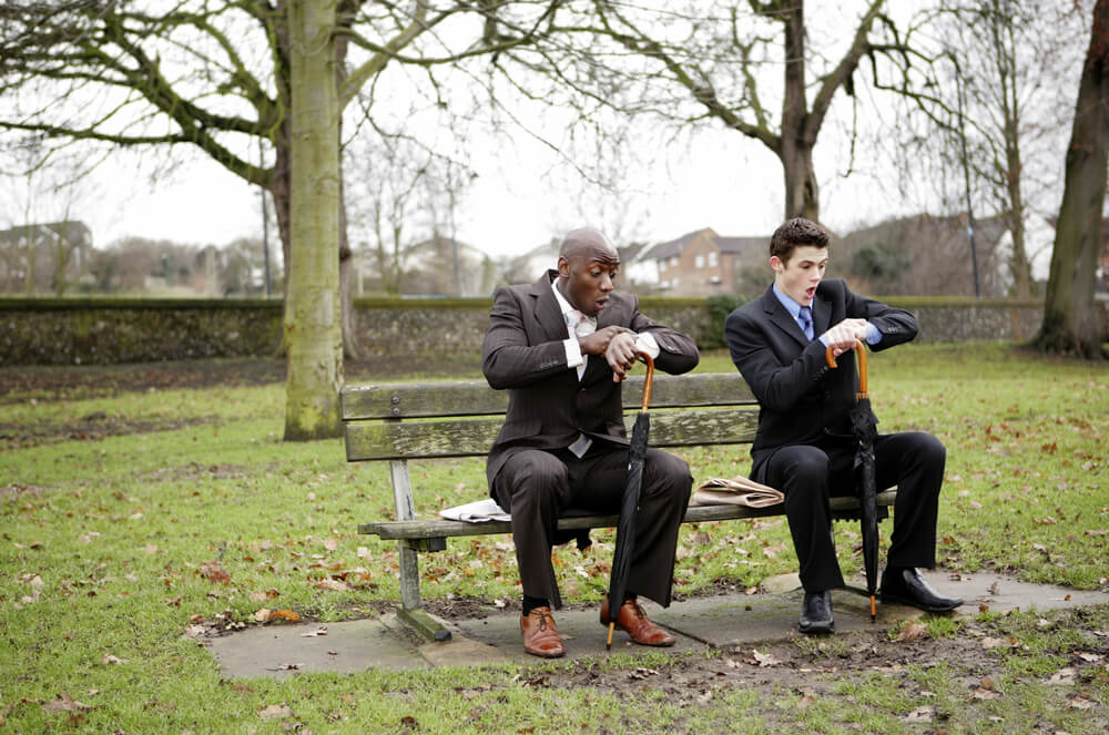 2 business men both checking their watches. Are they subonsciously influenced by each other?